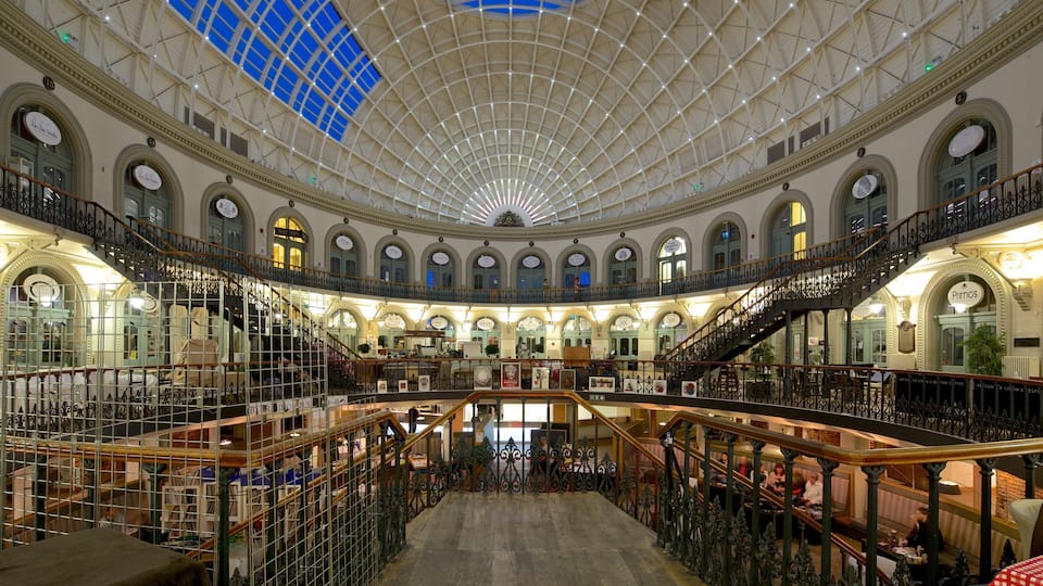 Un centro comercial amplio y de varios niveles, con barandillas decorativas y un alto techo abovedado de cristal.