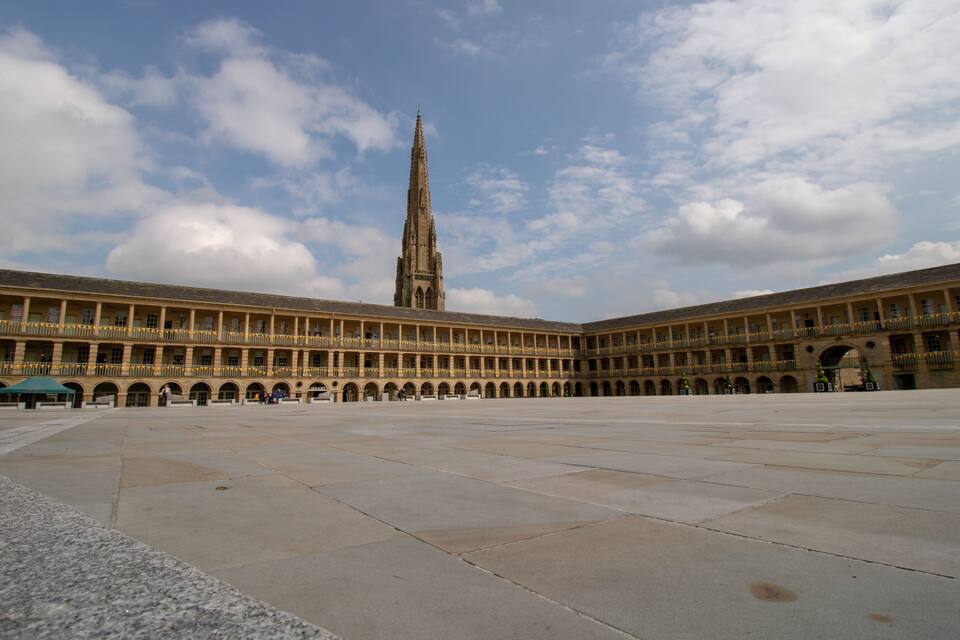 A large open courtyard with a tall, pointed tower in the background.