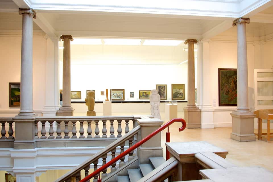 Un atrium majestuós amb columnes clàssiques, una escala de marbre i obres d'art exposades.