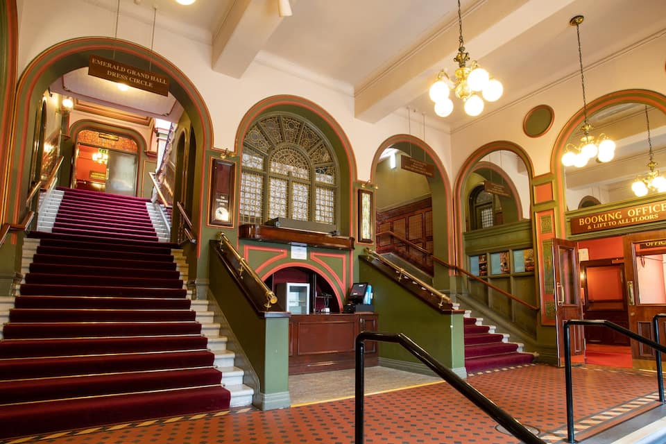 A grand staircase with red carpeted steps leading to a high ceiling with ornate decorations.