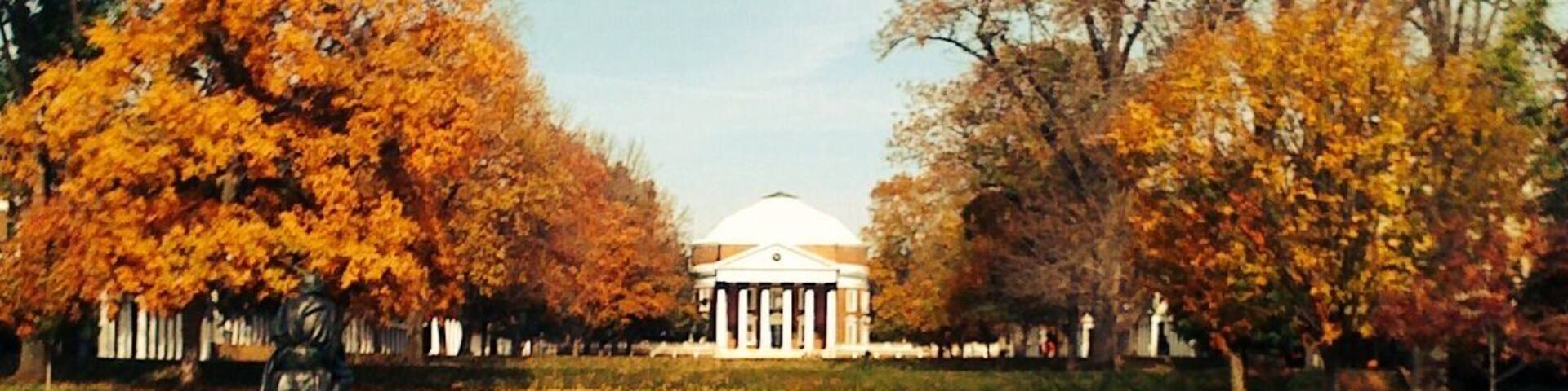 A park with a white building surrounded by trees with autumn foliage.