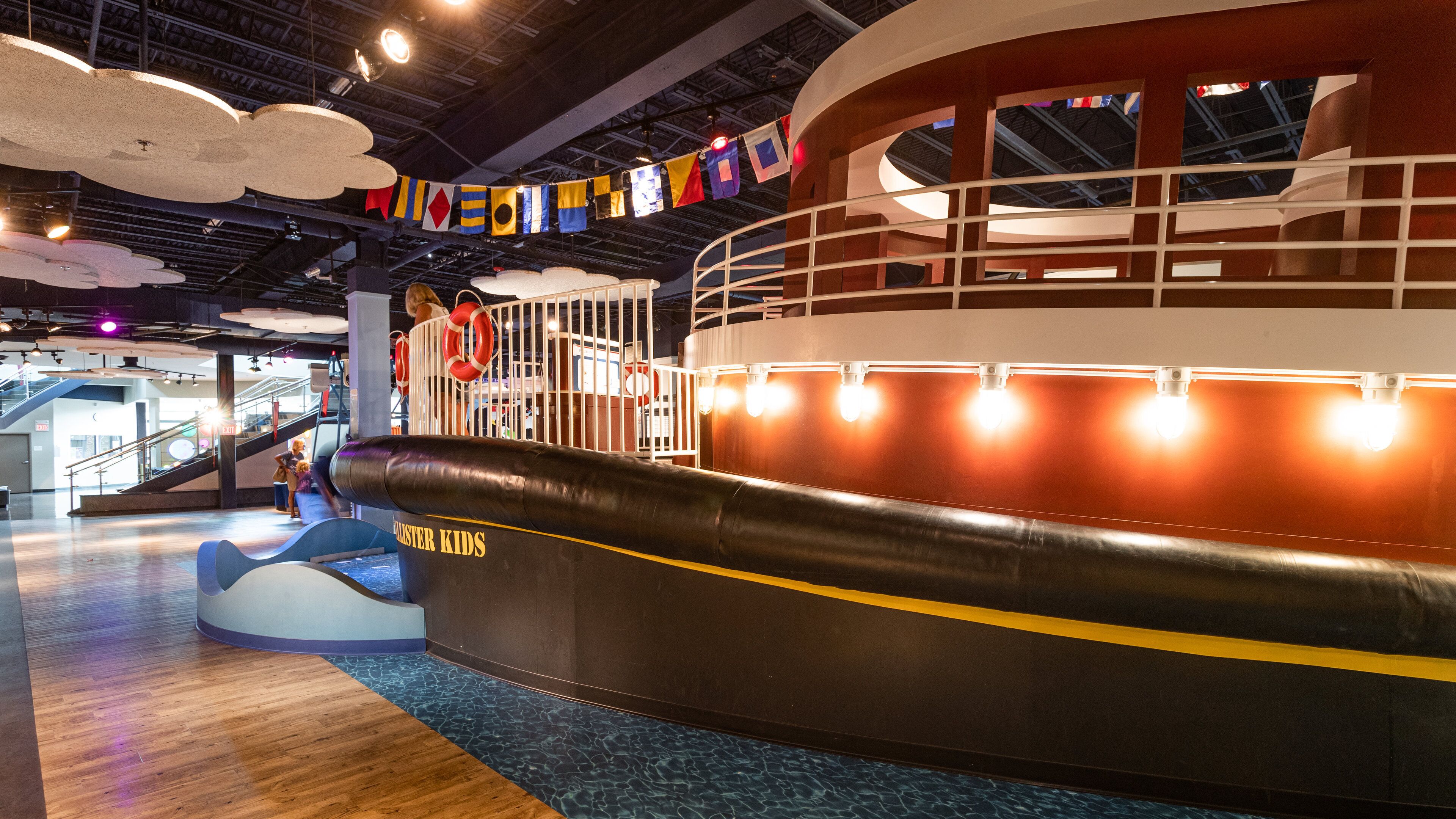 Zona de juegos infantiles con una gran estructura temática de barco, que incluye un timón y boyas salvavidas.