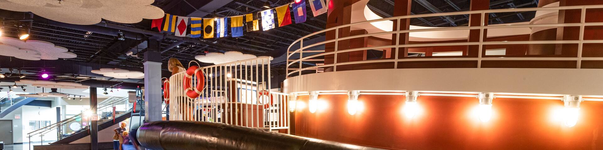 Zona de juegos infantiles con una gran estructura temática de barco, que incluye un timón y boyas salvavidas.