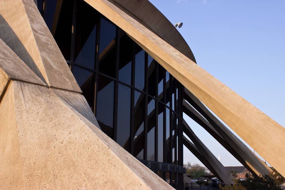 Una estructura arquitectònica moderna amb grans finestres de vidre i una estructura metàl·lica corba.