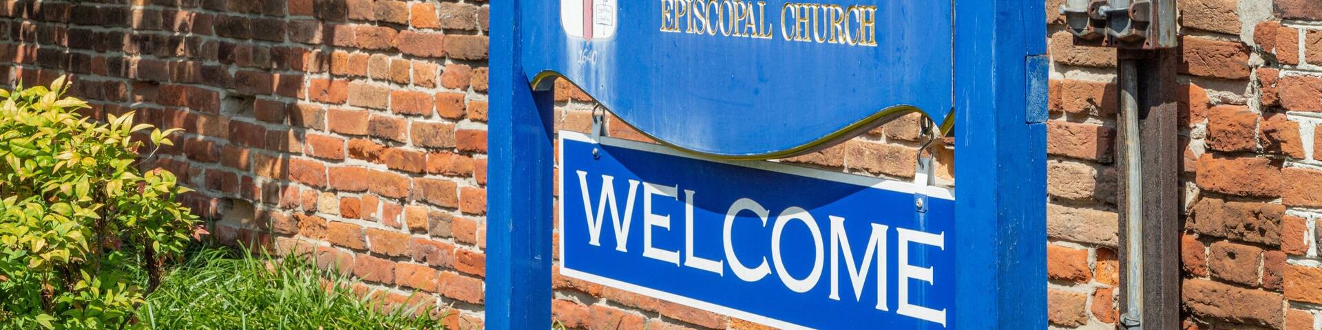 A blue sign with gold lettering that reads "Saint Paul's Episcopal Church" and "Welcome".