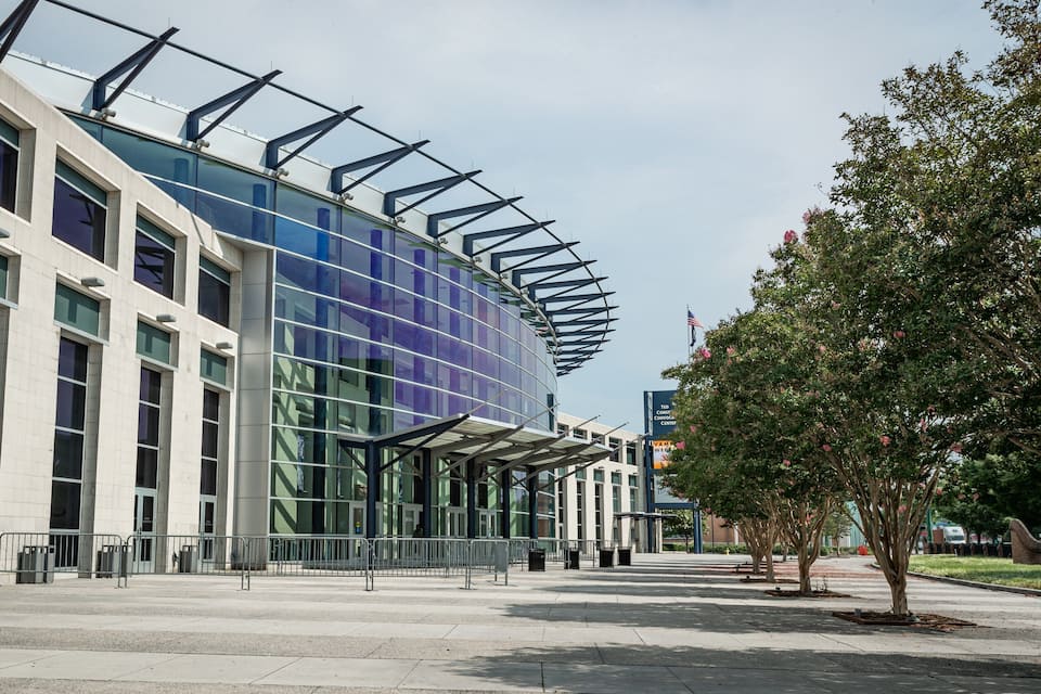 A modern building with a glass facade and a curved roof structure.