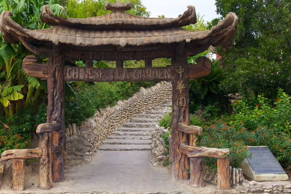Eingang eines traditionellen chinesischen Teehauses mit einer Steintreppe, die zu einem hölzernen Torbogen führt.