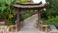 Entrada a un jardín de té chino tradicional, con una escalera de piedra que conduce a un arco de madera.