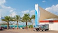 A coastal area with palm trees, a beach, and a large white structure with blue accents.