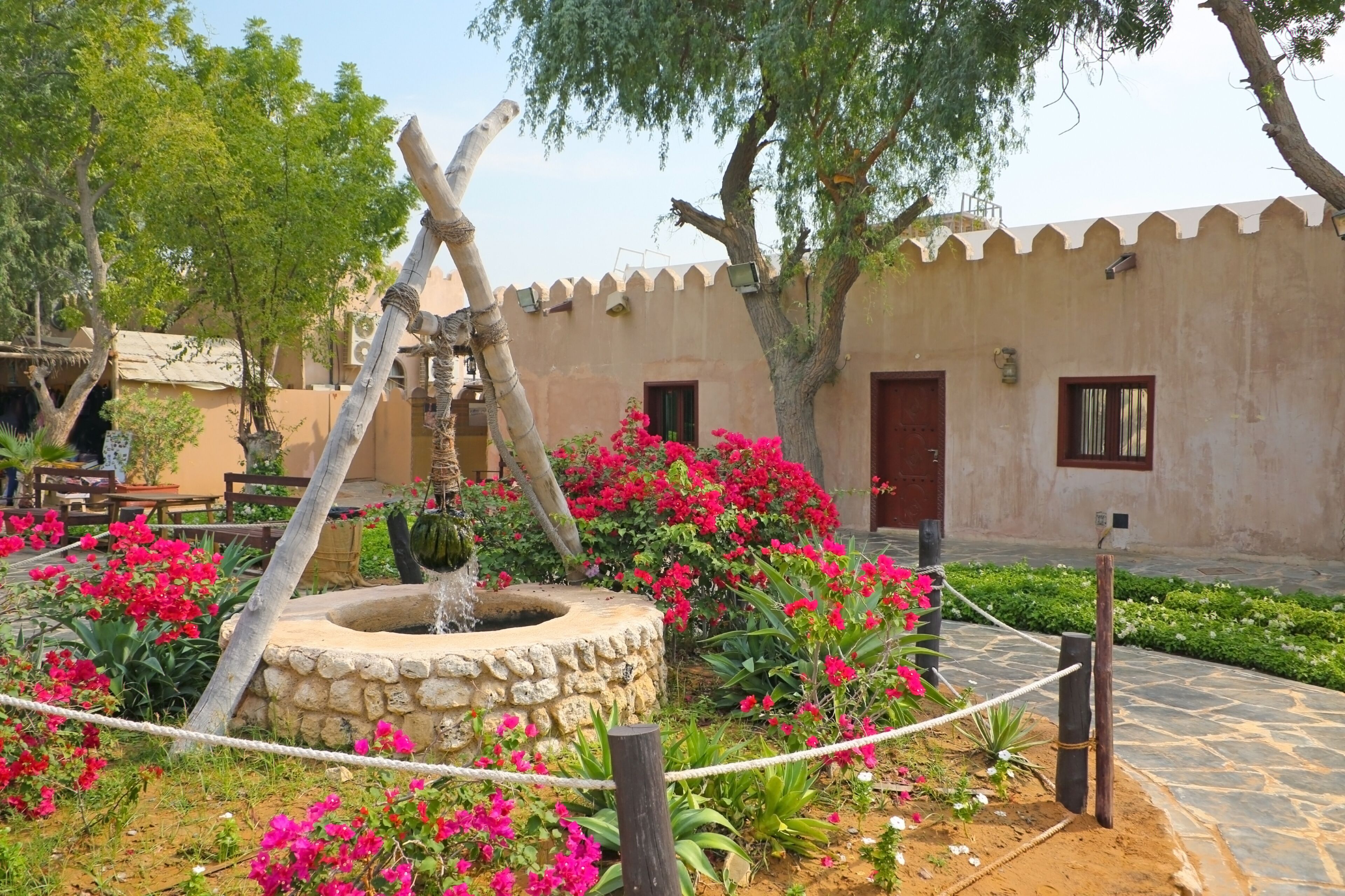 Traditional stone house and well in the front garden at the Heritage village, Abu Dhabi, United Arab Emirates.