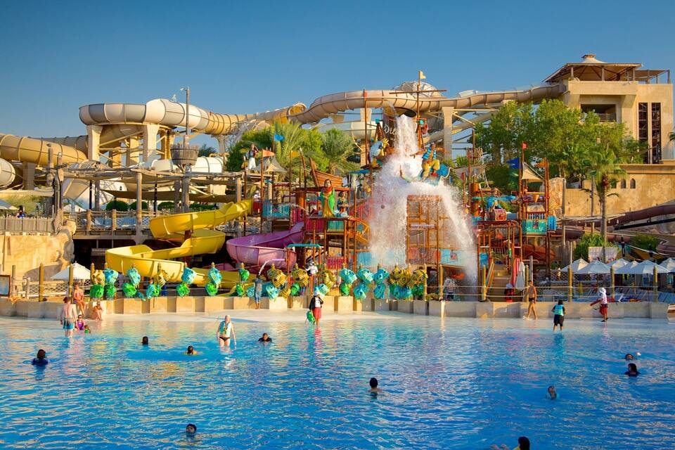 Ein Wasserpark mit großem Pool, mehreren Wasserrutschen und einer Wasserfall-Attraktion.