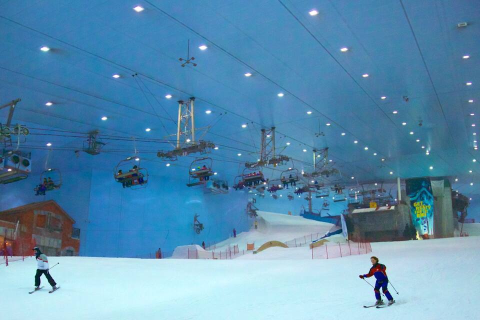 An indoor ski slope with artificial snow, ski lifts, and a ski instructor.