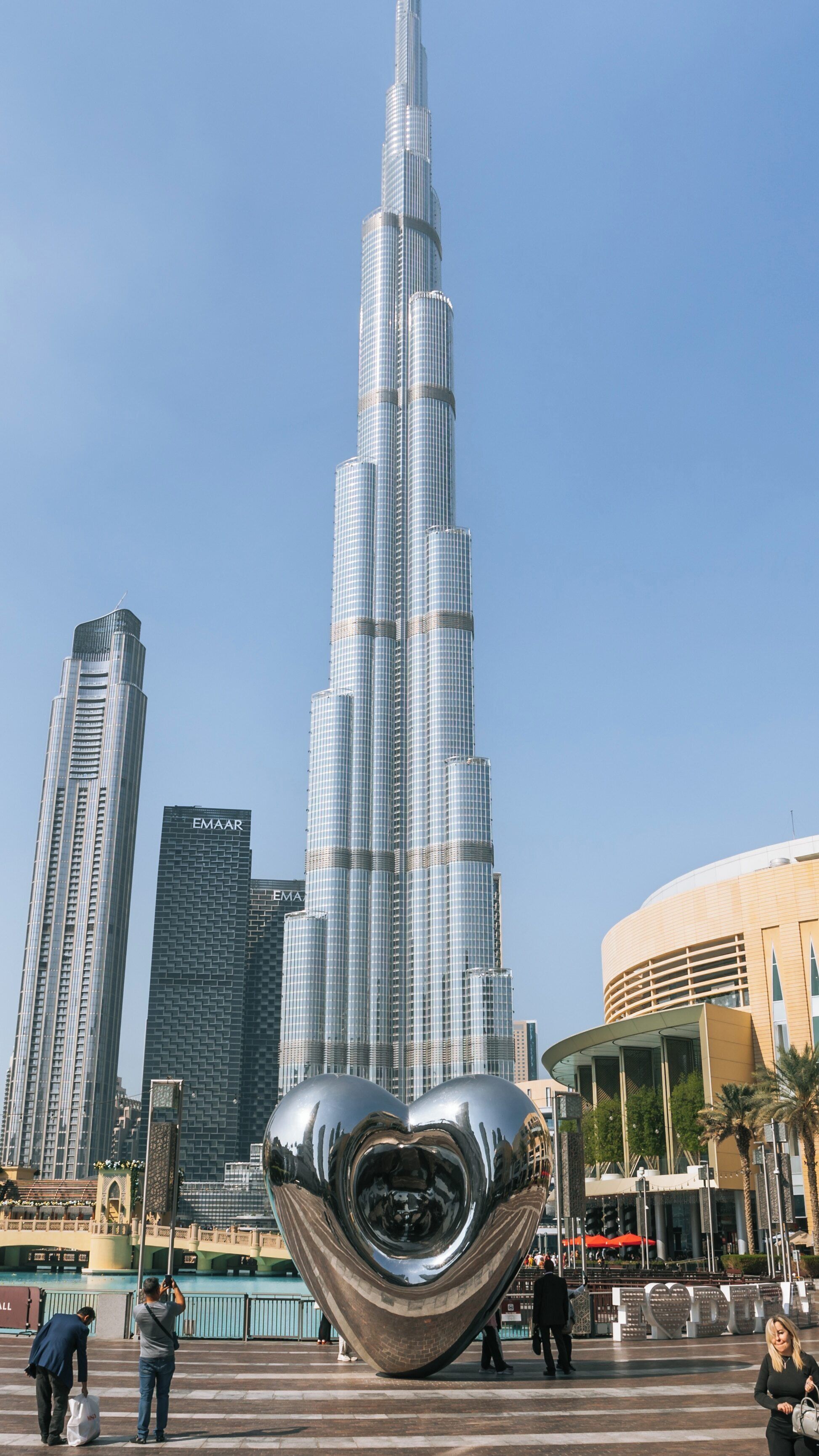 Burj Khalifa stands majestically in Downtown Dubai with a large heart sculpture in the foreground, showcasing modern architecture and vibrant city life