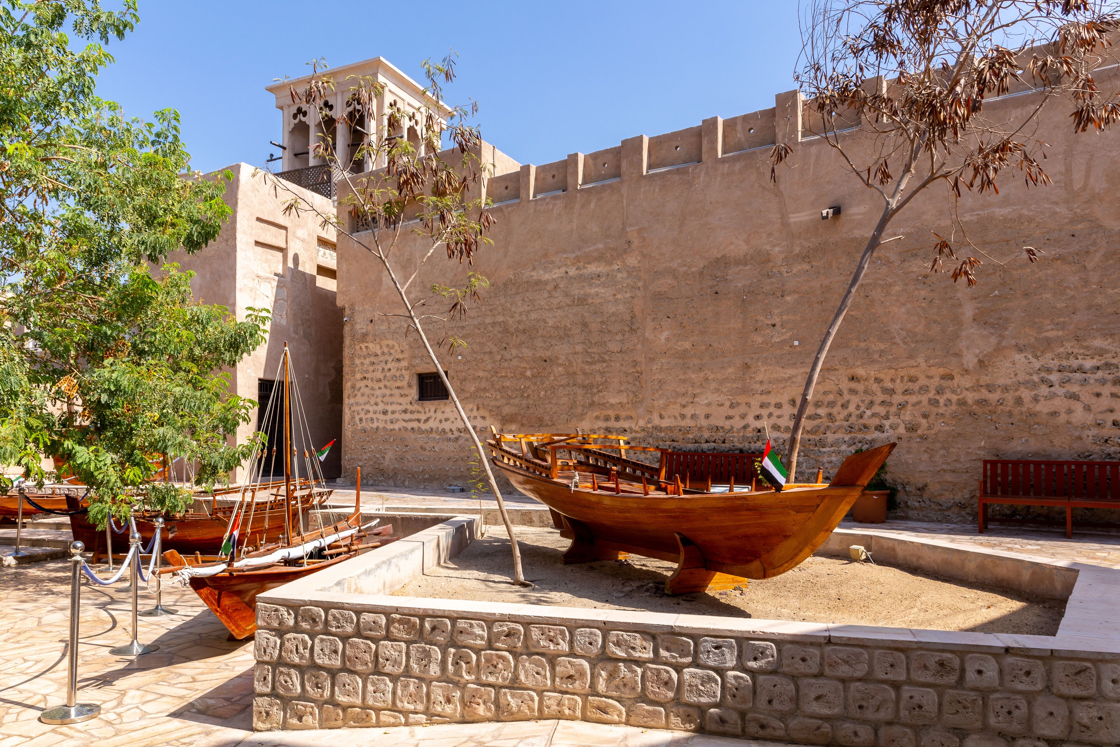 Small traditional wooden rowing boats - abras , with Al Fahidi Old Fort walls in the background, Al Fahidi Historical District, Dubai, United Arab Emirates.