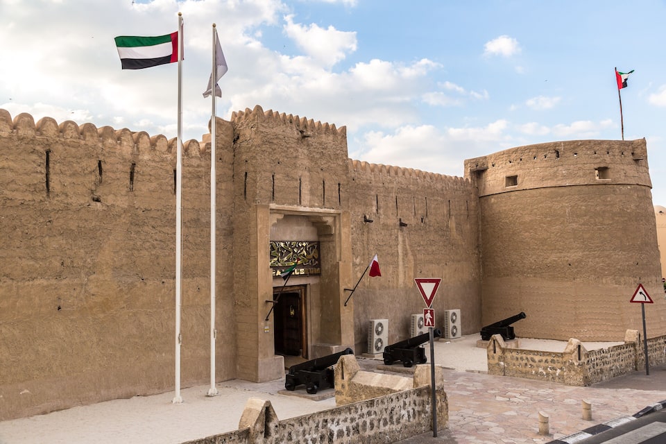 Una fortaleza histórica con banderas, cañones y la entrada a un museo.