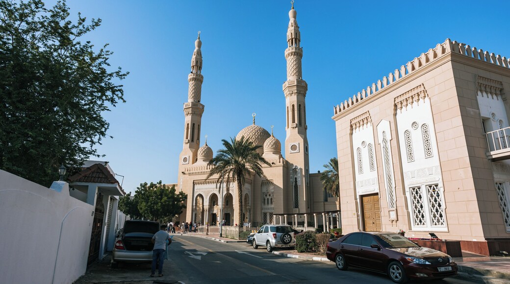 A mosque with two minarets and a large dome, surrounded by a street with cars and pedestrians.