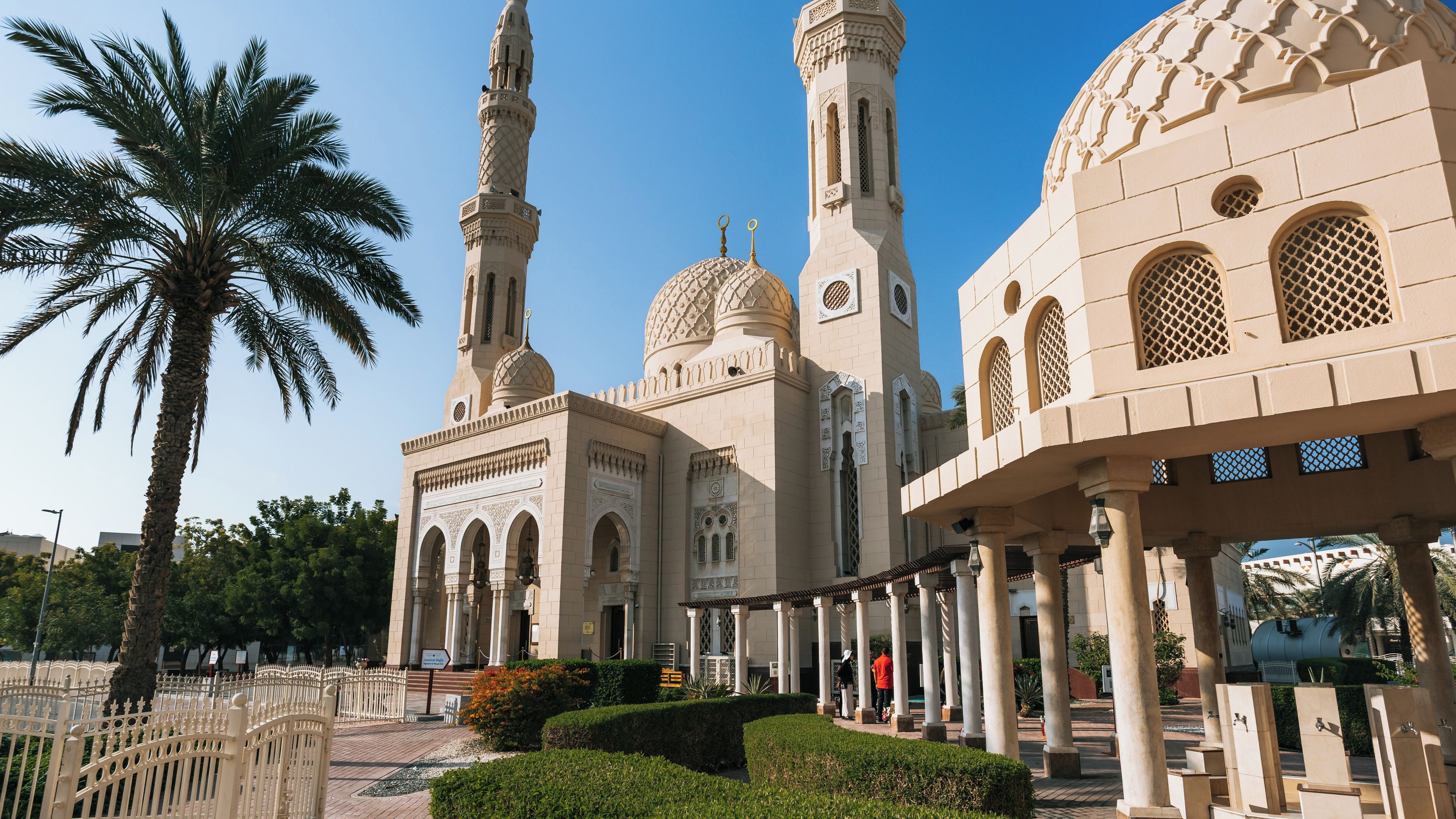 A mosque with a tall minaret, domes, and arches.