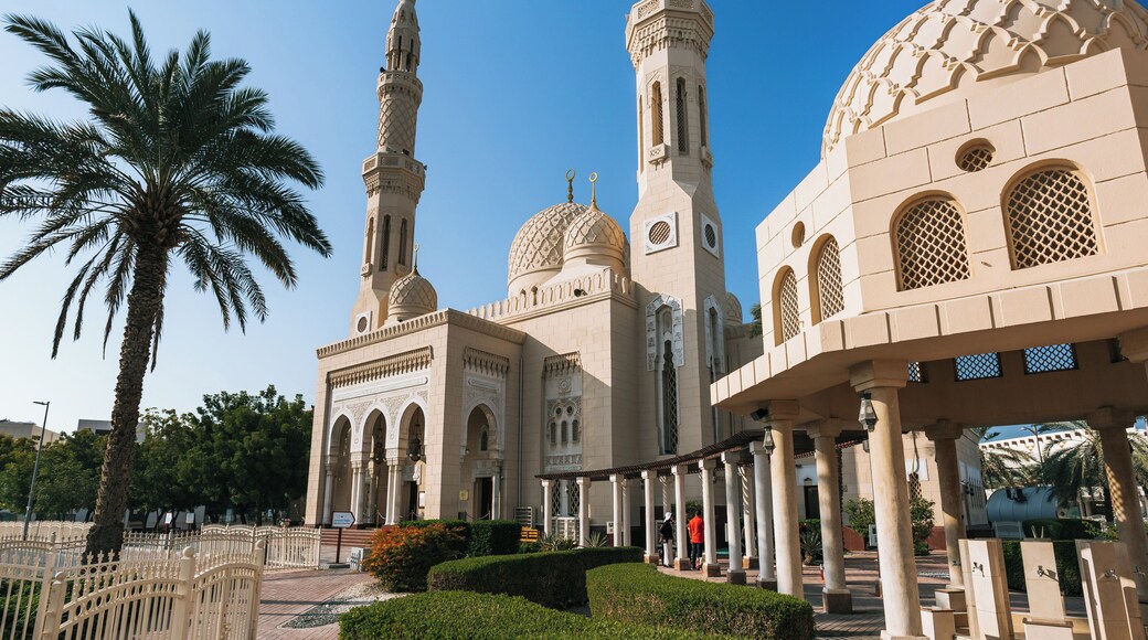 A mosque with a tall minaret, domes, and arches.