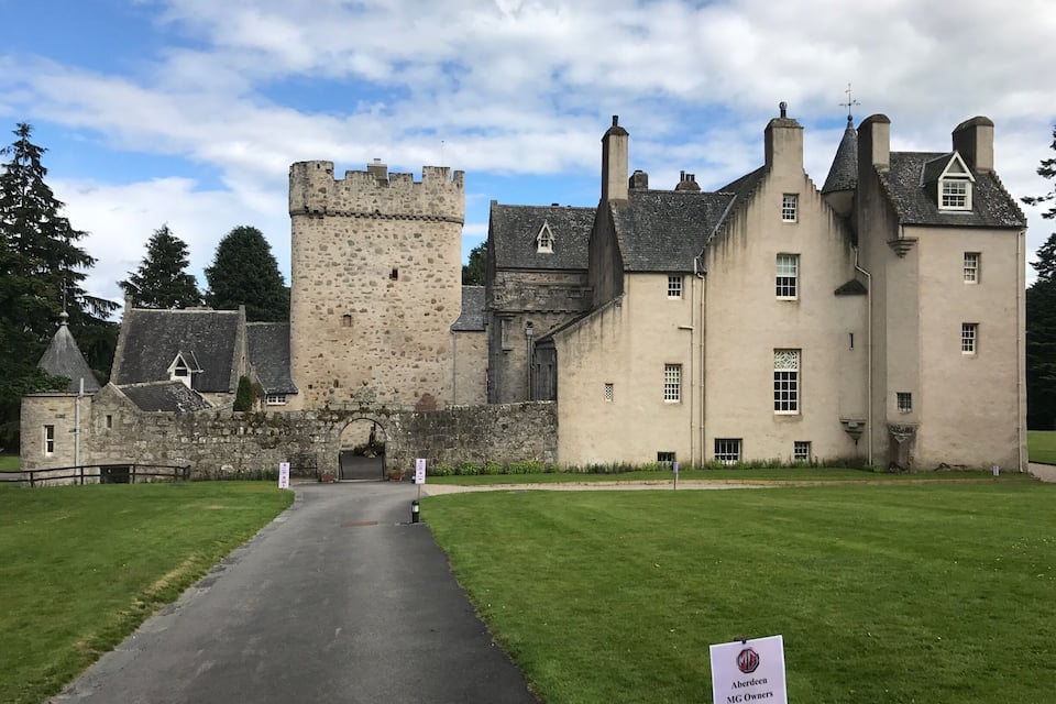 A castle with a stone tower and a paved entrance.