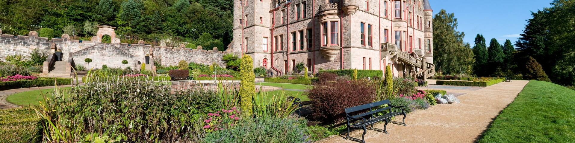 A large, historic castle with multiple towers and a well-maintained garden.