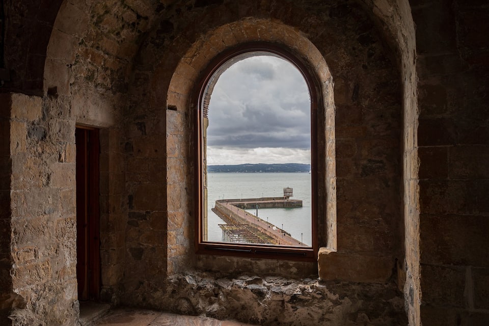 An arched window with a view of a dock and water.