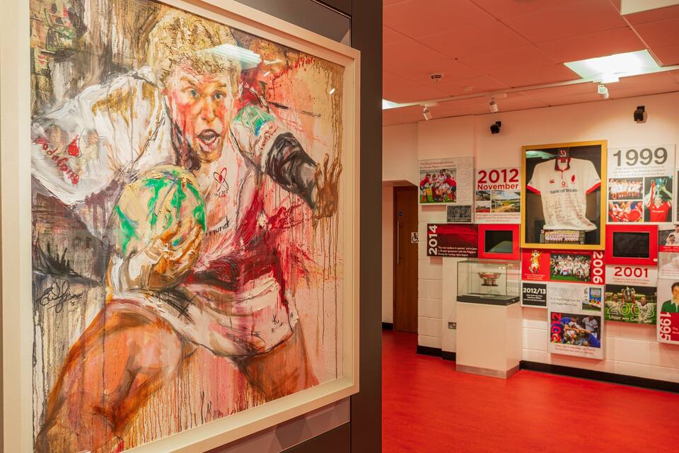 A sports hall with a large abstract painting and memorabilia from 1999 to 2014.