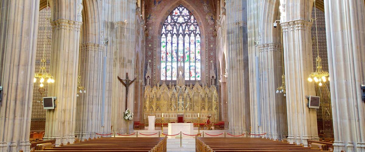 A grand cathedral interior with tall columns, a large stained glass window, and ornate altar.