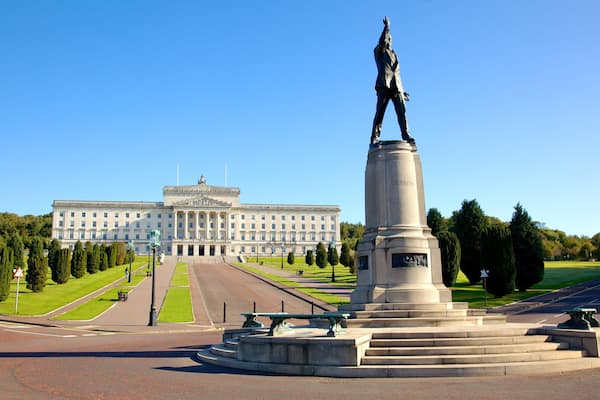 Un monument surmonté d’une statue, un grand bâtiment en arrière-plan et une pelouse bien entretenue.