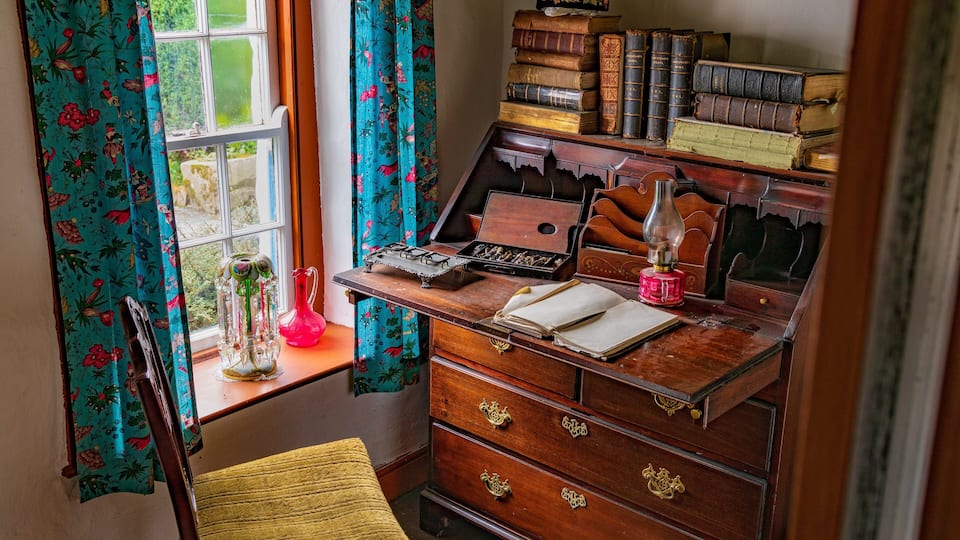 Un escritorio de madera con libros antiguos, una máquina de escribir y una lámpara.