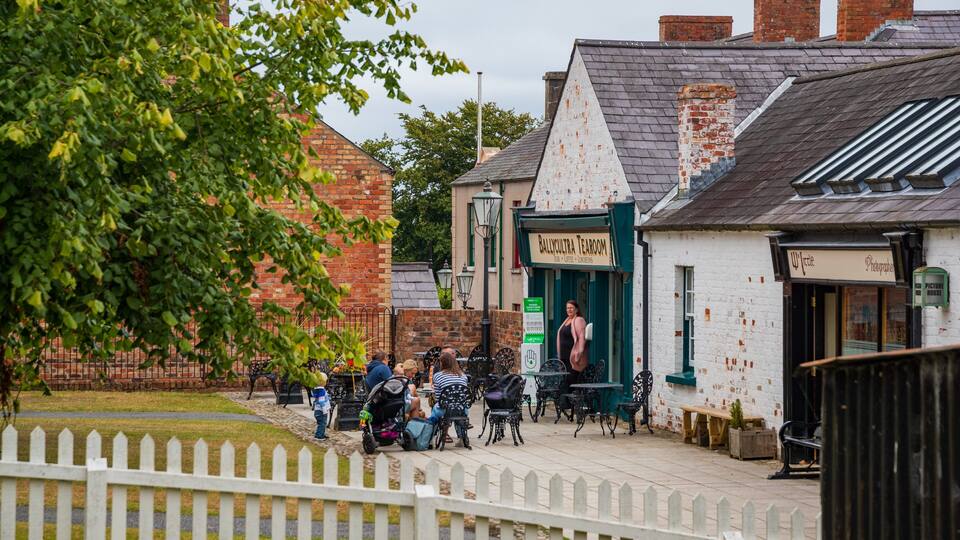 A quaint street with a white building labeled "Ballycultra Tearoom" and a photographer's studio.