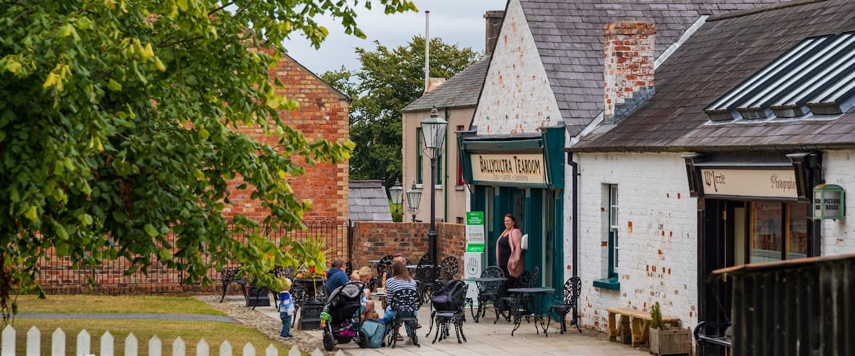 A quaint street with a white building labeled "Ballycultra Tearoom" and a photographer's studio.