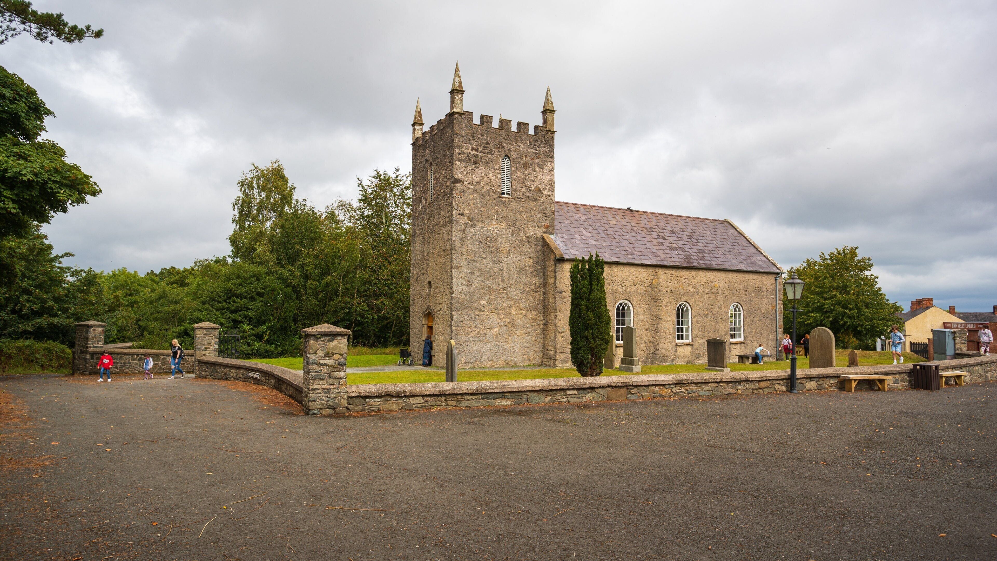 A historic stone church with a tall tower and a cemetery.