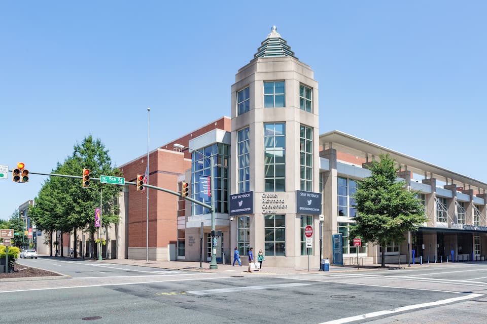 Un edificio con una torre, un letrero que dice “Greater Richmond Convention Center” y una intersección con semáforos.