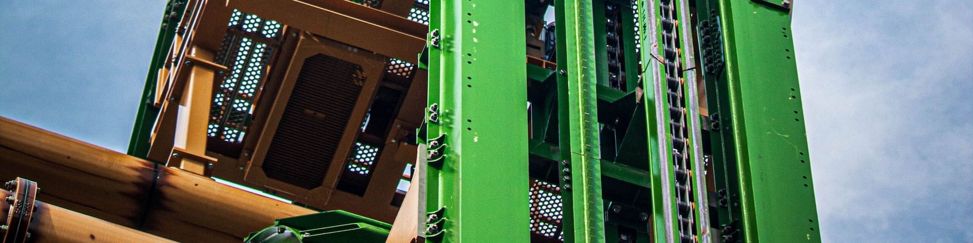 A green roller coaster track against a blue sky.