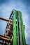 Eine grüne Achterbahnstrecke vor blauem Himmel.