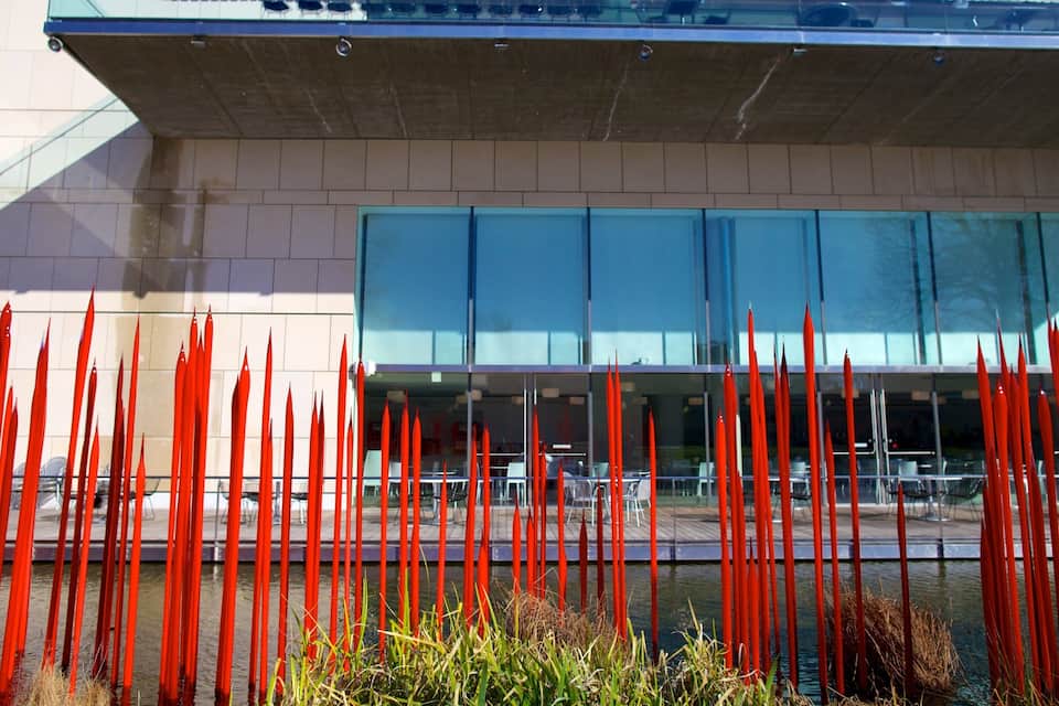 A modern building with a glass facade and red vertical elements in the foreground.