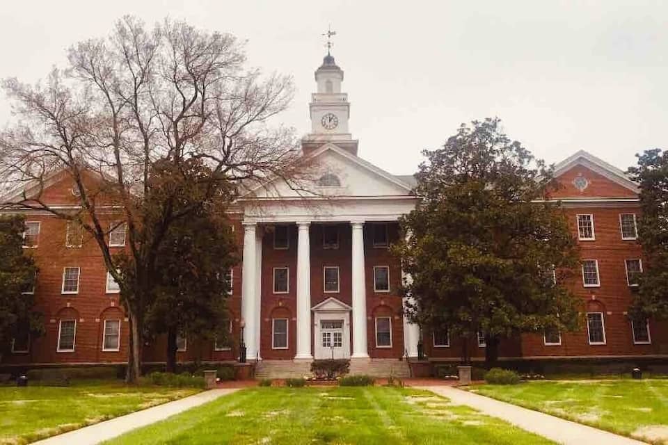 A large red brick building with a central portico and a clock tower.