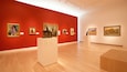 An art gallery with red walls and wooden floors.