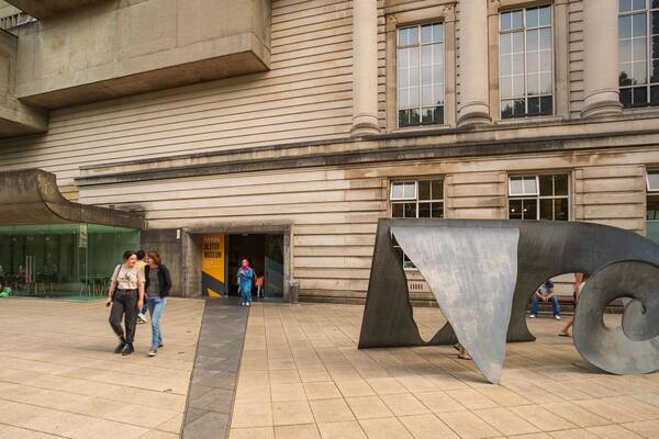 A large metal sculpture in front of a building with a sign for the Ulster Museum.