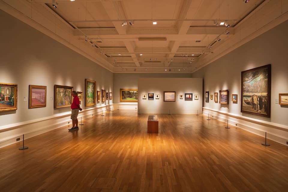 An art gallery with wooden floors and paintings on the walls.