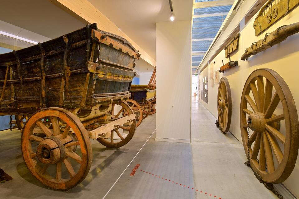 A historical wagon with large wooden wheels on display in a museum.