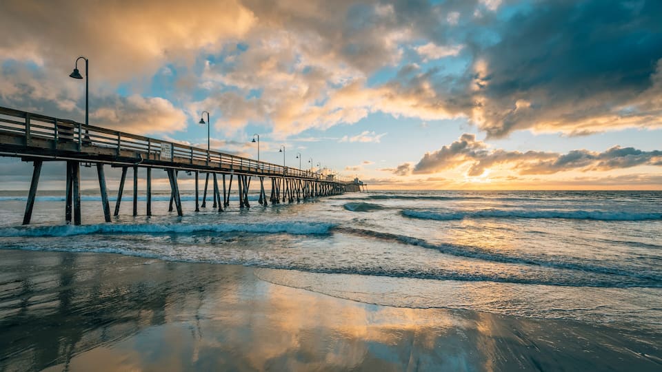 A pier extending into the ocean with waves lapping at its base.