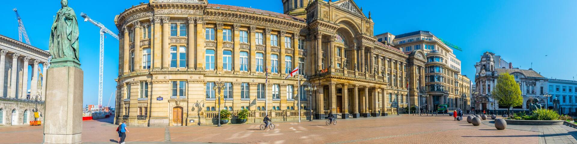 A historic building with classical architecture, a statue, and a clear blue sky.