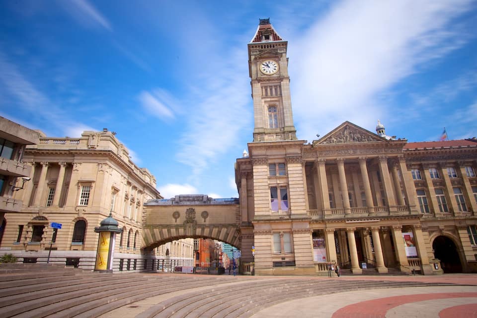 A historic building with a clock tower, a large archway, and steps leading up to the entrance.
