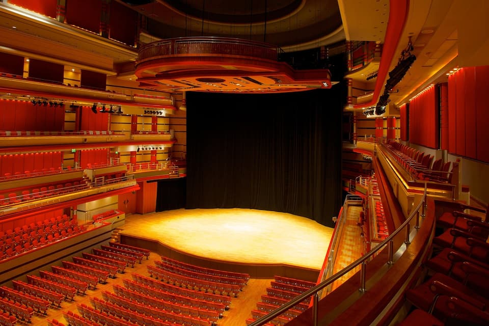 A large indoor theater with multiple balconies and rows of red seats.
