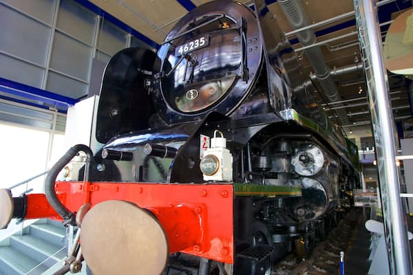 Eine Dampflokomotive mit der Nummer 46235, in einem Gebäude mit Metalltreppen und Industrieausstattung.