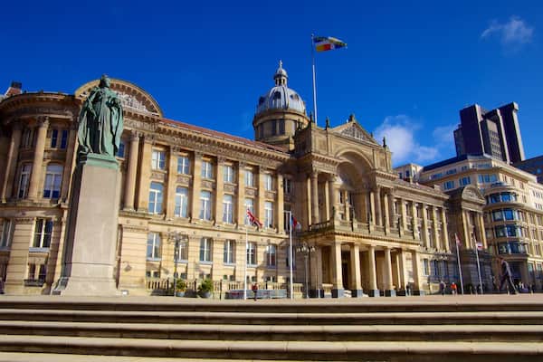 A historic building with classical architecture, a statue, and flags.