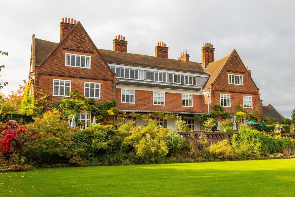 A large brick house with multiple chimneys and a well-maintained garden.