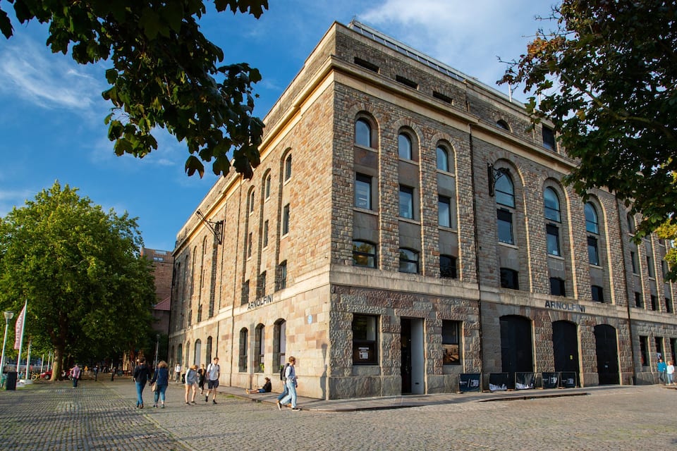 Een historisch stenen gebouw met gebogen ramen en een bord waarop