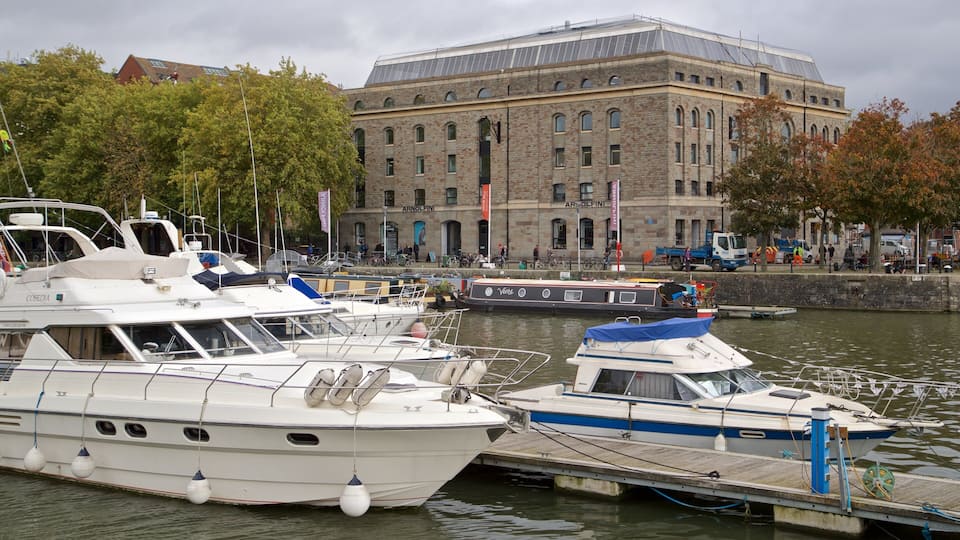 En lystbådehavn med flere både i havnen, en stor bygning med spændt buer og et bybillede i baggrunden.